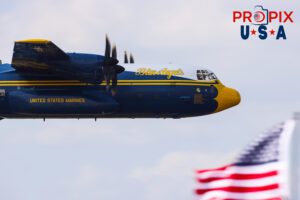 Fat Albert and Old Glory. Blue Angels C-130 supply and transport aircraft performing a low pass in front of the crowd and an American flag at the 2025 Sun N Fun Airshow in Lakeland Florida. The pilots can easily be identified and a crew member is seen in a cargo window waving to the crowd. Captain Sam Petko (USMC) Captain Isaac Becker (USMC) Major Josh Horman (USMC) Aircraft code: C130 Airport code(s): KLAL, LAL