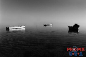 Boats at anchor in Hawaii. This is an images of three small wood boats moored in the shallow waters just North of Kaneohe Hawaii. As the sun was rising, it was illuminating the eastwardly sides of the boats with the warm tropical Hawaiian sun. The faintest ocean ripples were skimming past these heavy boats without being noticed.