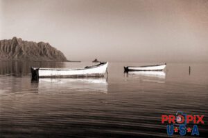 Chinaman Boats. This image is of two boats moored in the shallow waters North of Kaneohe Hawaii with Chinamans hat island in the background. This photo was taken in the 1990's with a film camera.