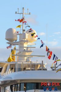 Mega yacht mast with colorful flags at sunrise