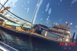 Just a rinse..! The stern of a mega yacht rinsed with water and reflecting other yachts docked at the marina.