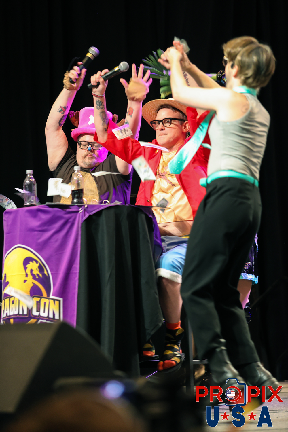 2025 Dragon Con Masquerade hosts. Tony Gowell and Eddie McClintock. Money flying. Attempted bribery by a contestant. (one of our favorite images). Photo date: 8-31-2025 Dragoncon