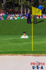 2018 Masters tournament champion Patrick Reed seen in a sand trap on course with his wife Justine watching in the background at Augusta National golf course Georgia