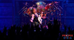 Smiling Dave Murray of Iron Maiden reaches his hand towards the crowd in appreciation of their positive reaction to the show.